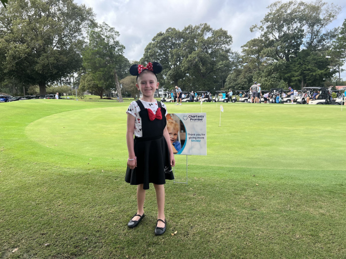 Little girl standing in front of a Chartway Promise Foundation sign